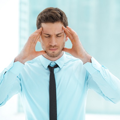 Man holding head because of headache pain caused by TMJ disorder.