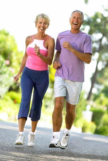 Older man and woman exercising by brisk walking on a road.